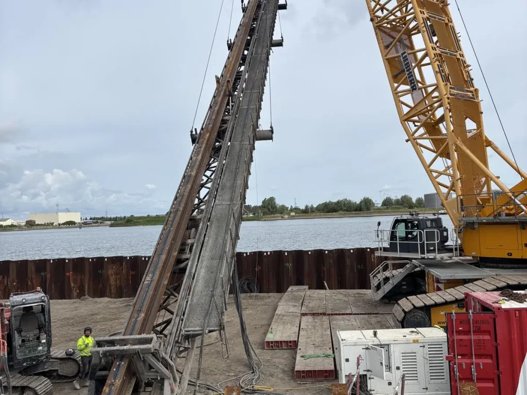 Vliegende makelaar aan een rupskraan op een funderingswerf aan het water