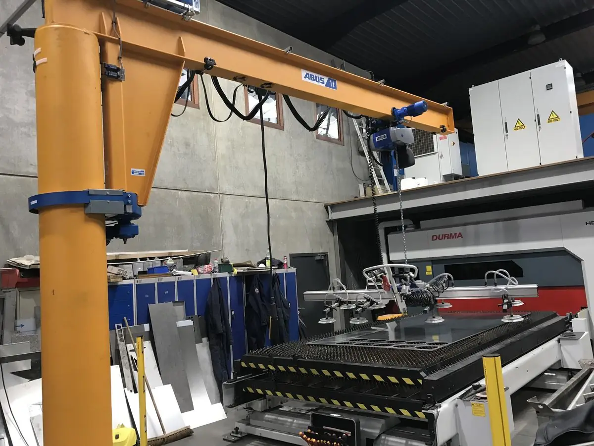 Zwenkkraan met vacuümgrijper naast een lasersnijtafel