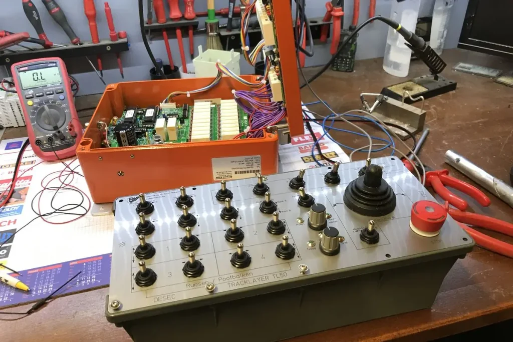 Zender en geopende ontvanger op de werkbank in het atelier, met multimeter en soldeerbout