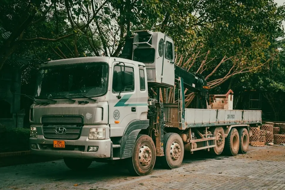Vrachtwagen met laadkraan op een werf (voorbeeldbeeld)
